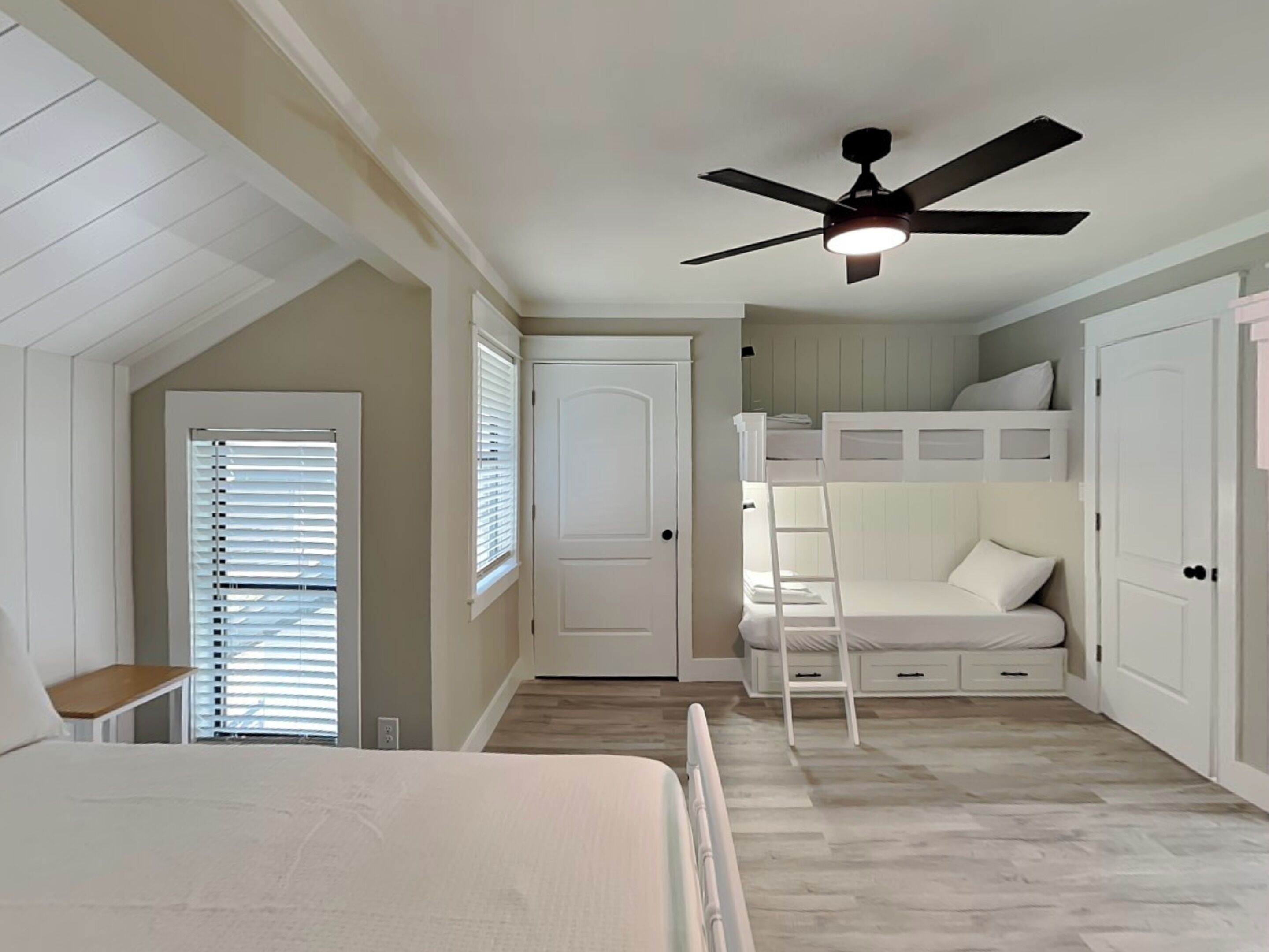 A bedroom with a bunk bed, a ceiling fan, and a window with blinds.