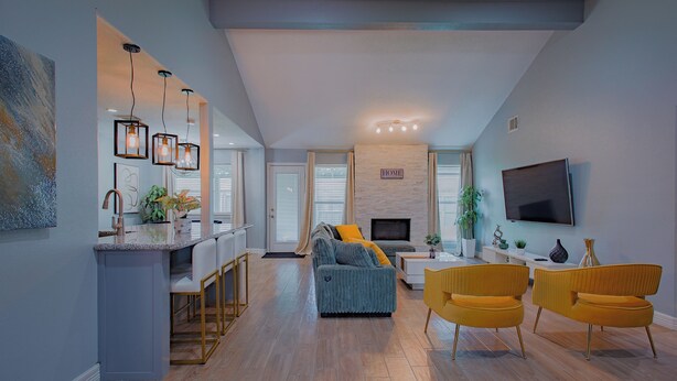 A modern living room with a sofa, yellow chairs, and a TV mounted on the wall.