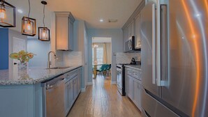 A modern kitchen with stainless steel appliances, a granite countertop, and pendant lighting.