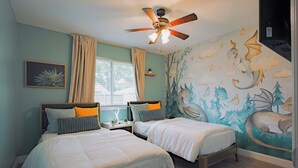 A bedroom with two beds, a ceiling fan, a window with curtains, and a mural on the wall.