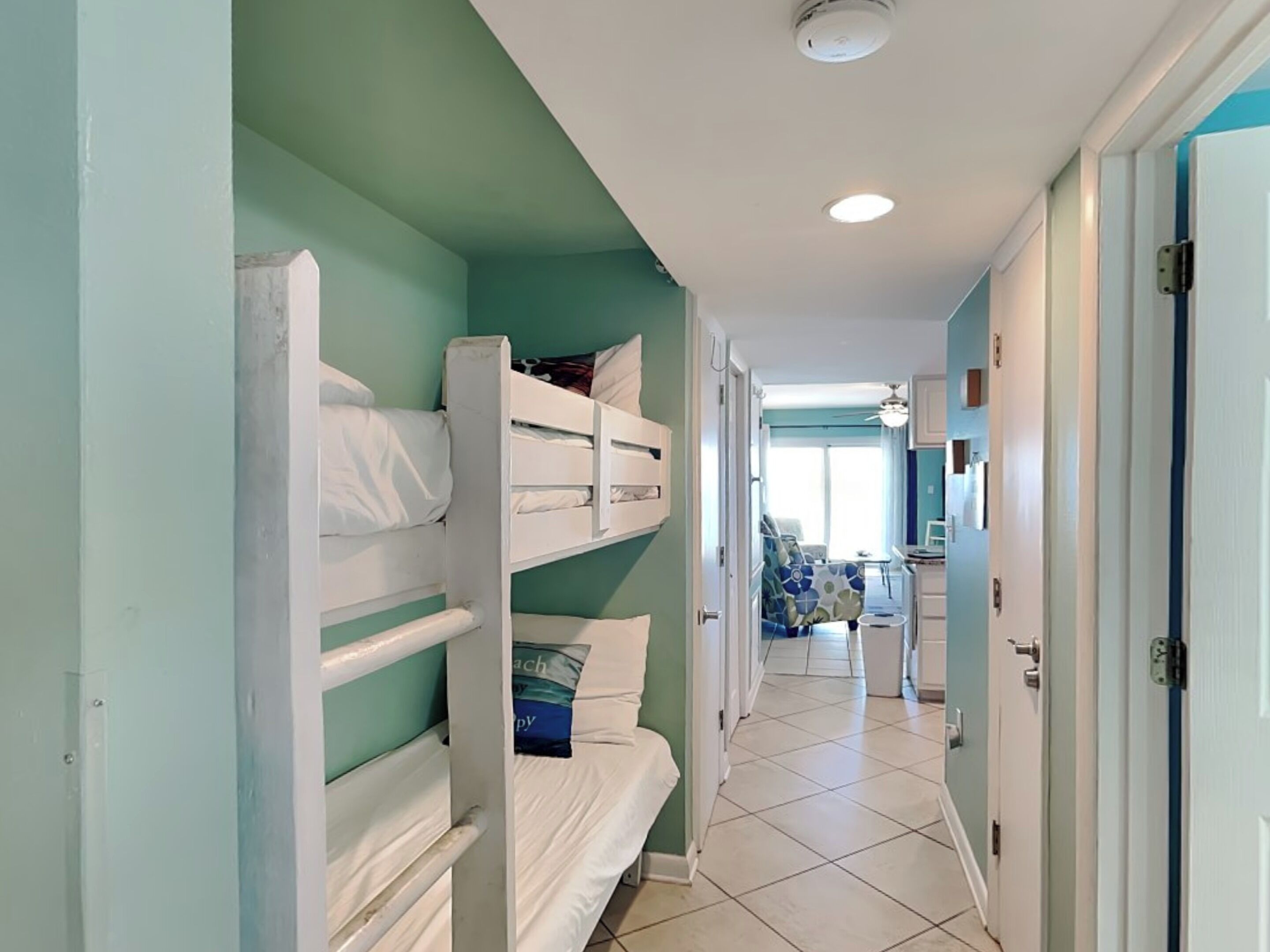 Un pasillo con literas, una kitchenette y un baño a lo lejos.
