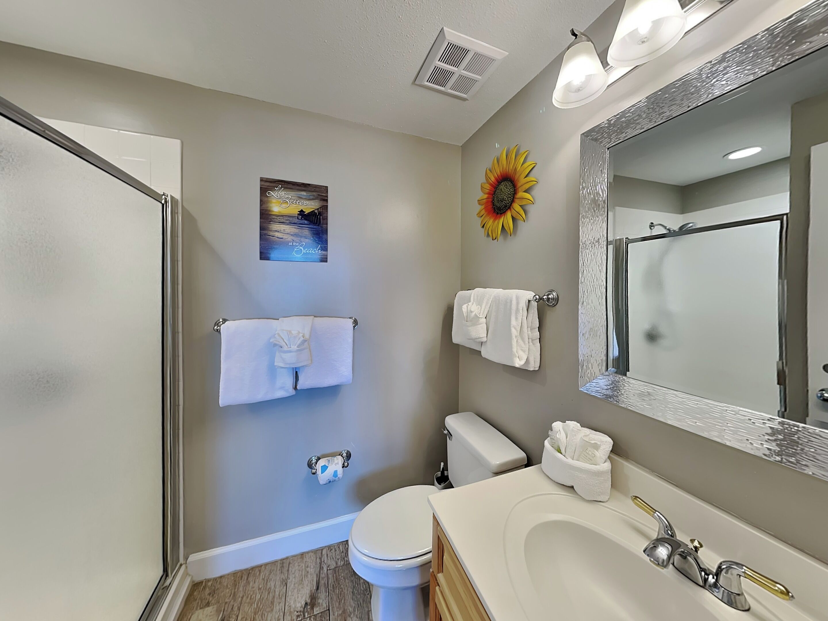 A bathroom with a shower, toilet, sink, and a large mirror.