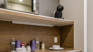 A compact kitchenette with a microwave, coffee maker, and a small refrigerator. - Wenceslao By Homirent (Queretaro)