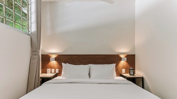A neatly made bed with white linens, two bedside tables with lamps, and a wooden headboard. - Wenceslao By Homirent (Queretaro)