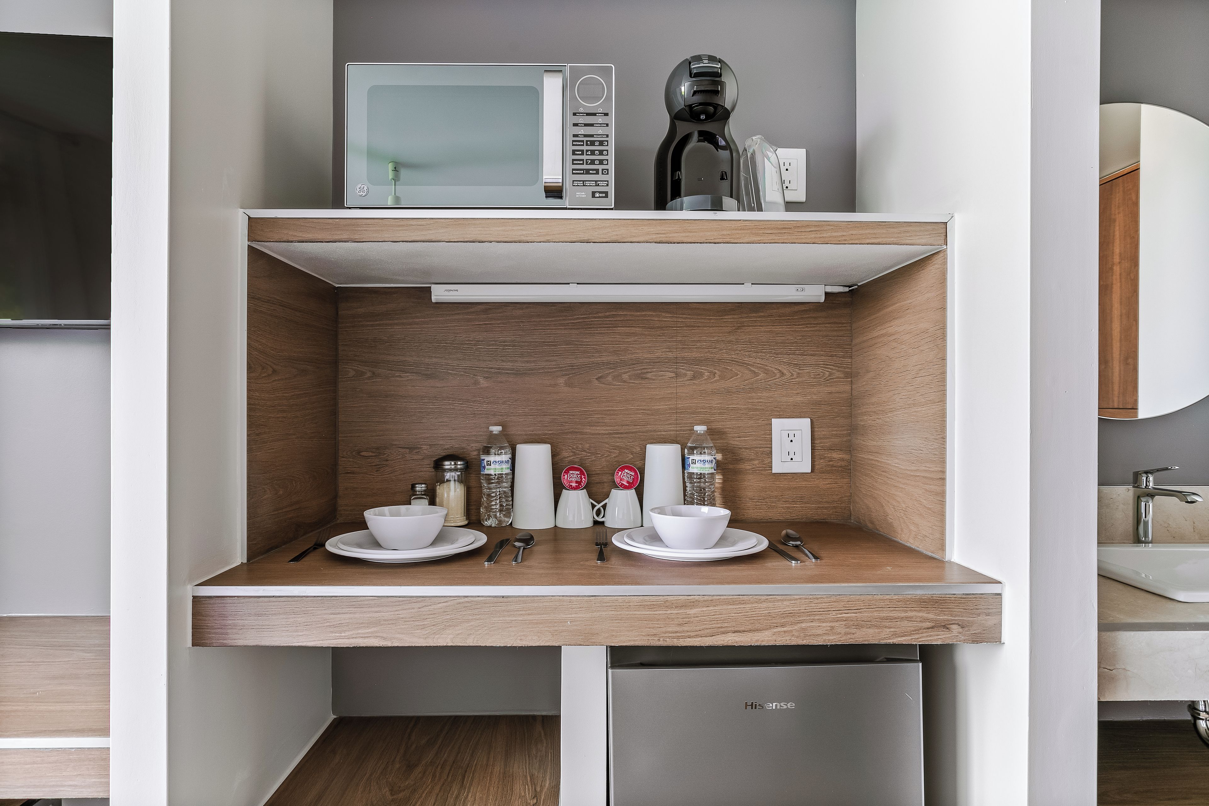 A compact kitchenette with a microwave, coffee maker, and a small sink.