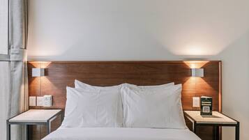 A hotel room with a wooden headboard, two bedside tables with lamps, and a bed with white bedding.