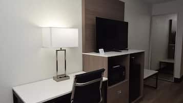 A hotel room with a desk, a chair, a TV, and a wardrobe.