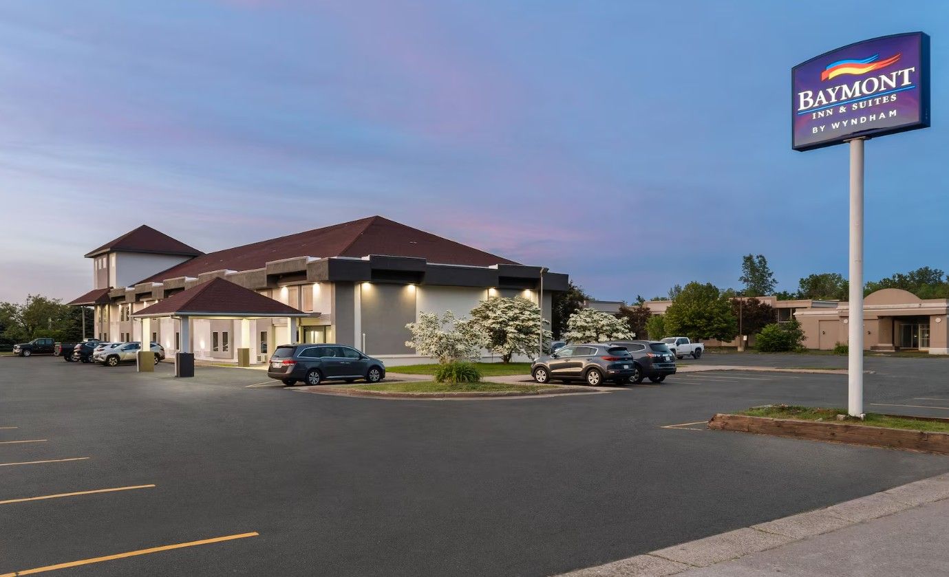 Un Baymont Inn & Suites by Wyndham con parcheggio e un edificio a tetto rosso.