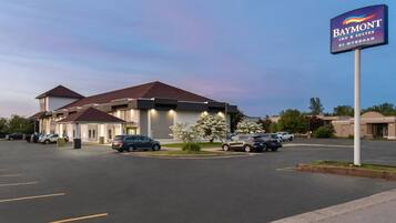 Un Baymont Inn & Suites by Wyndham con parcheggio e un edificio a tetto rosso.