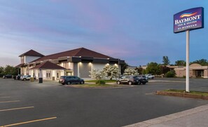 A Baymont Inn & Suites by Wyndham with a parking lot and a building with a red roof. - Baymont By Wyndham Batavia - Darien Lake (Elba)