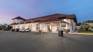 A modern hotel with a covered entrance, multiple parking spaces, and a well-lit facade. - Baymont By Wyndham Batavia - Darien Lake (Elba)