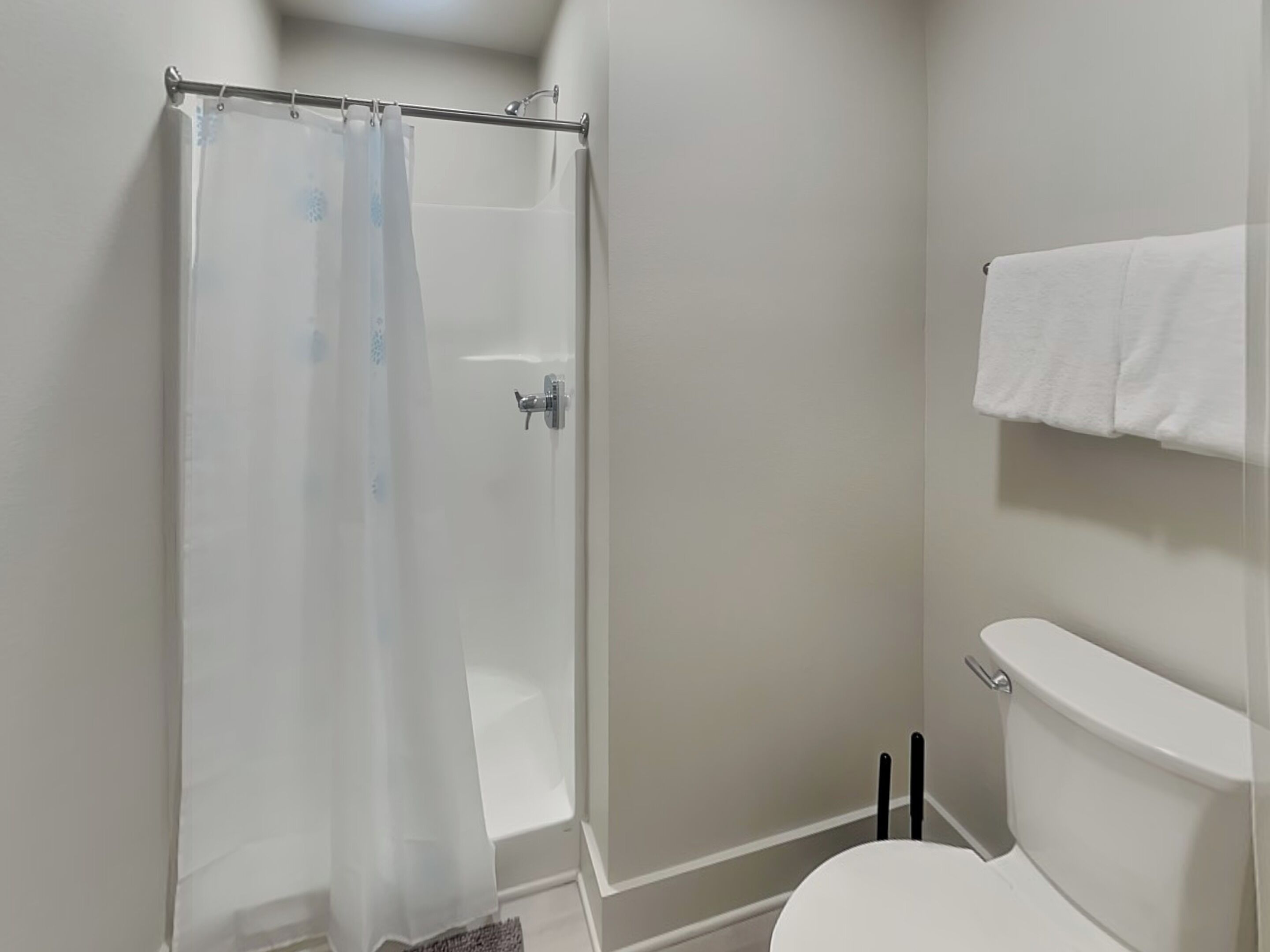 A bathroom with a shower, toilet, and towel rack.