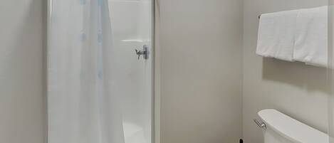 A bathroom with a shower, toilet, and towel rack.