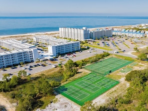 A coastal hotel complex with multiple buildings, a parking area, and a tennis court. - Royal Gulf Beach & Racquet Club #5816 by Southern Vacation Rentals (Gulf Shores)