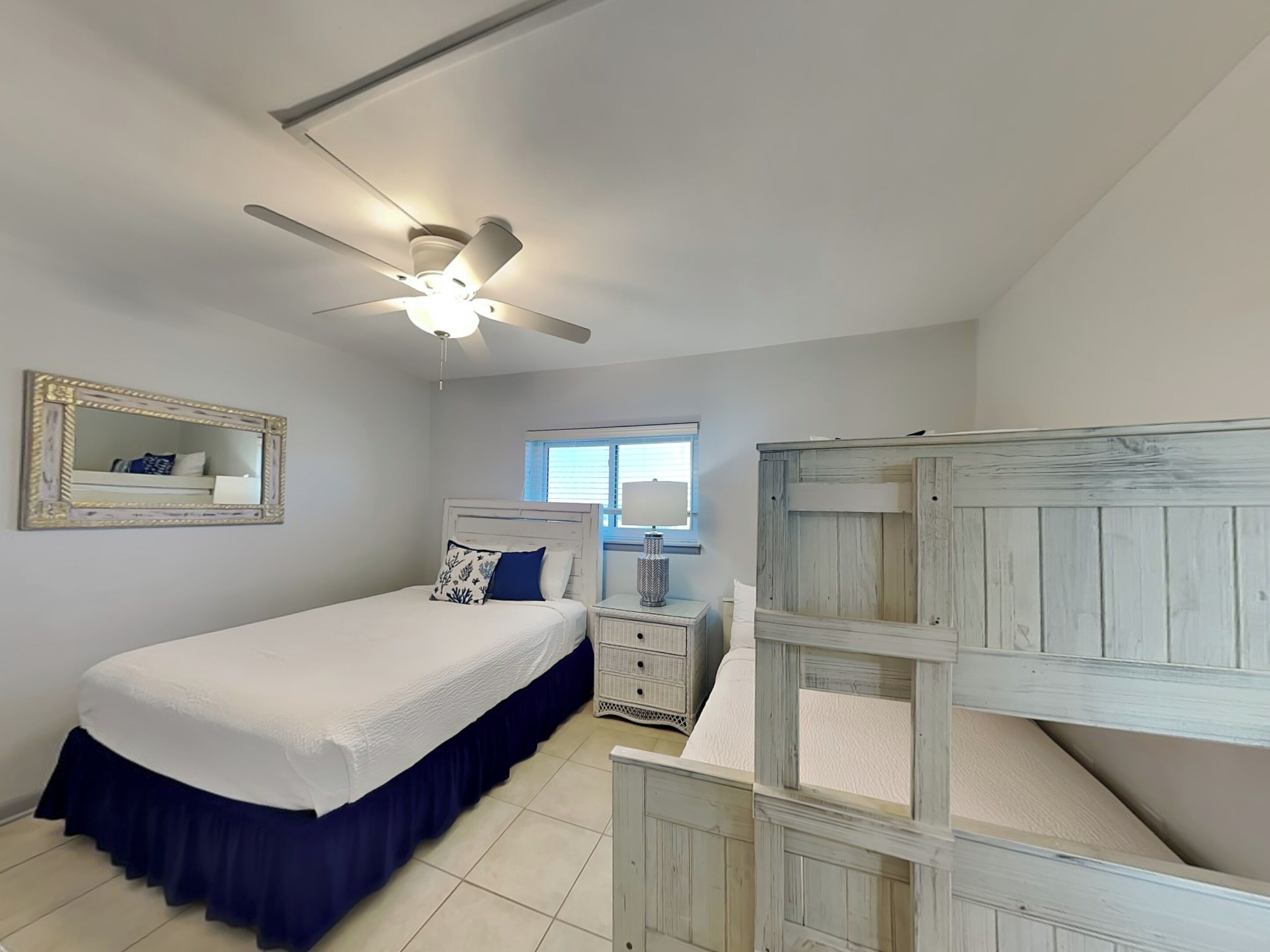 A bedroom with a bed, a nightstand, a dresser, a ceiling fan, and a window.