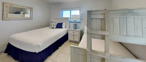 A bedroom with a bed, a nightstand, a dresser, a ceiling fan, and a window.