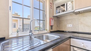 Una cocina con un lavamanos doble, una estufa y una ventana con vistas a edificios.