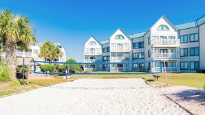 A beachfront hotel with multiple-story buildings, a sandy beach in the foreground, and a clear blue sky. - Gulf Shores Plantation #4206 by Southern Vacation Rentals (Gulf Shores)