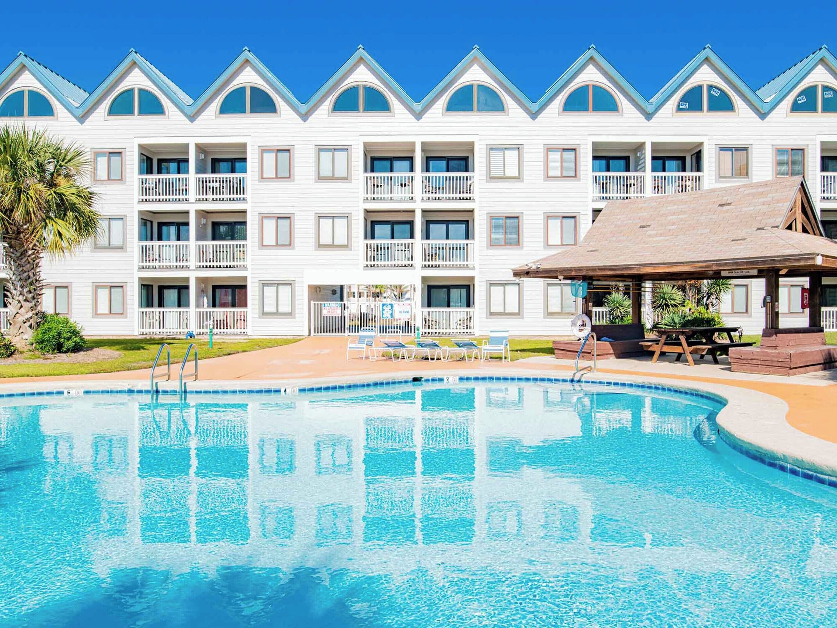 Un hôtel doté d’une piscine, de plusieurs balcons et d’un patio couvert.