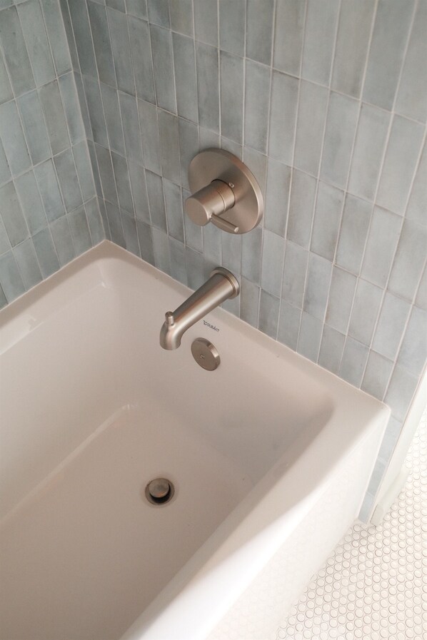 A bathroom with a white sink, a wall-mounted faucet, and a tiled backsplash.