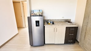 Una cocina compacta con refrigerador, pileta y mostrador.