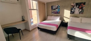 Quarto com cama, escrivaninha e cadeira. Há uma janela e uma porta.