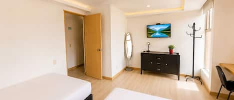 Habitació d'hotel amb dos llits, televisió, penjador i escriptori.