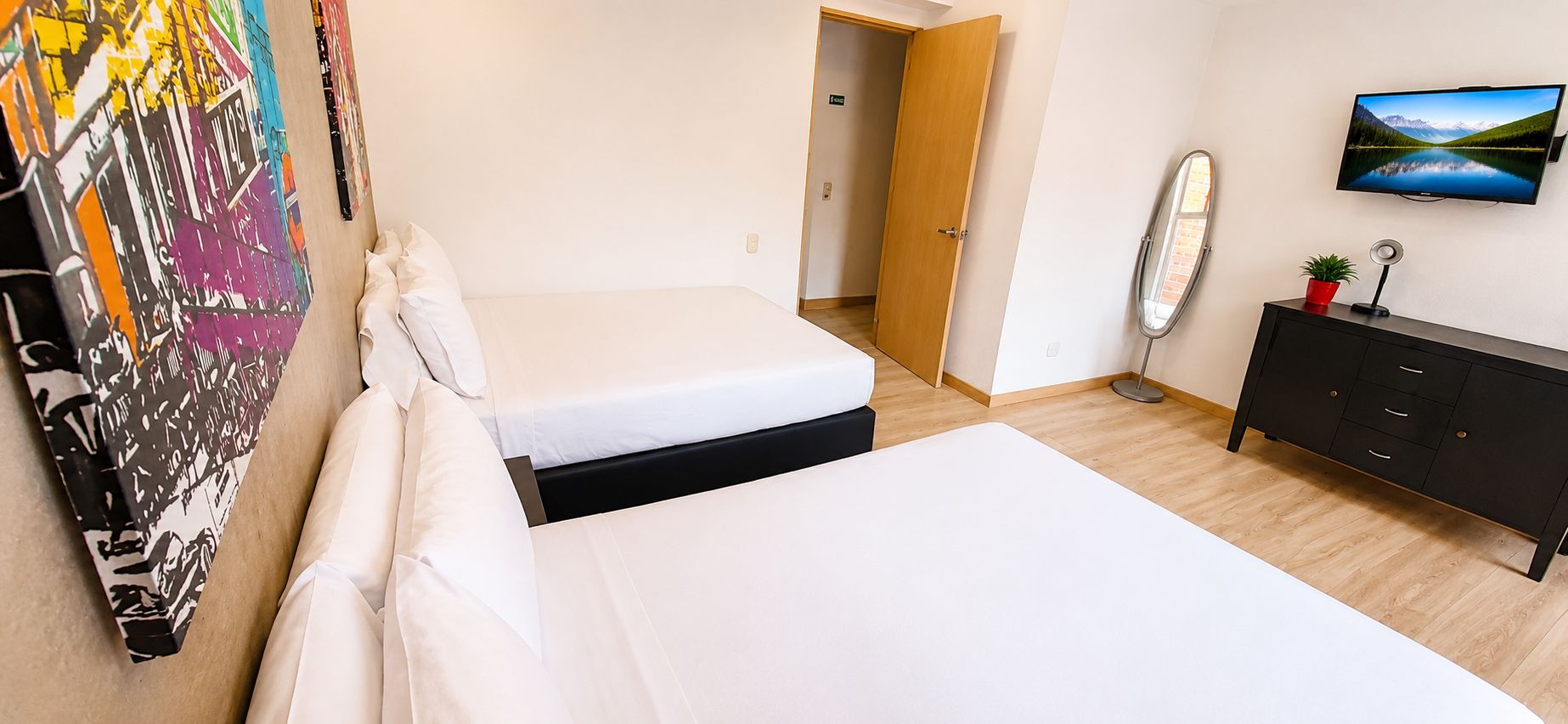 Une chambre d’hôtel avec deux lits, une télévision, une commode et un tableau au mur.
