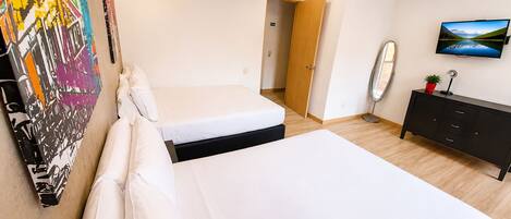 Une chambre d’hôtel avec deux lits, une télévision, une commode et un tableau au mur.