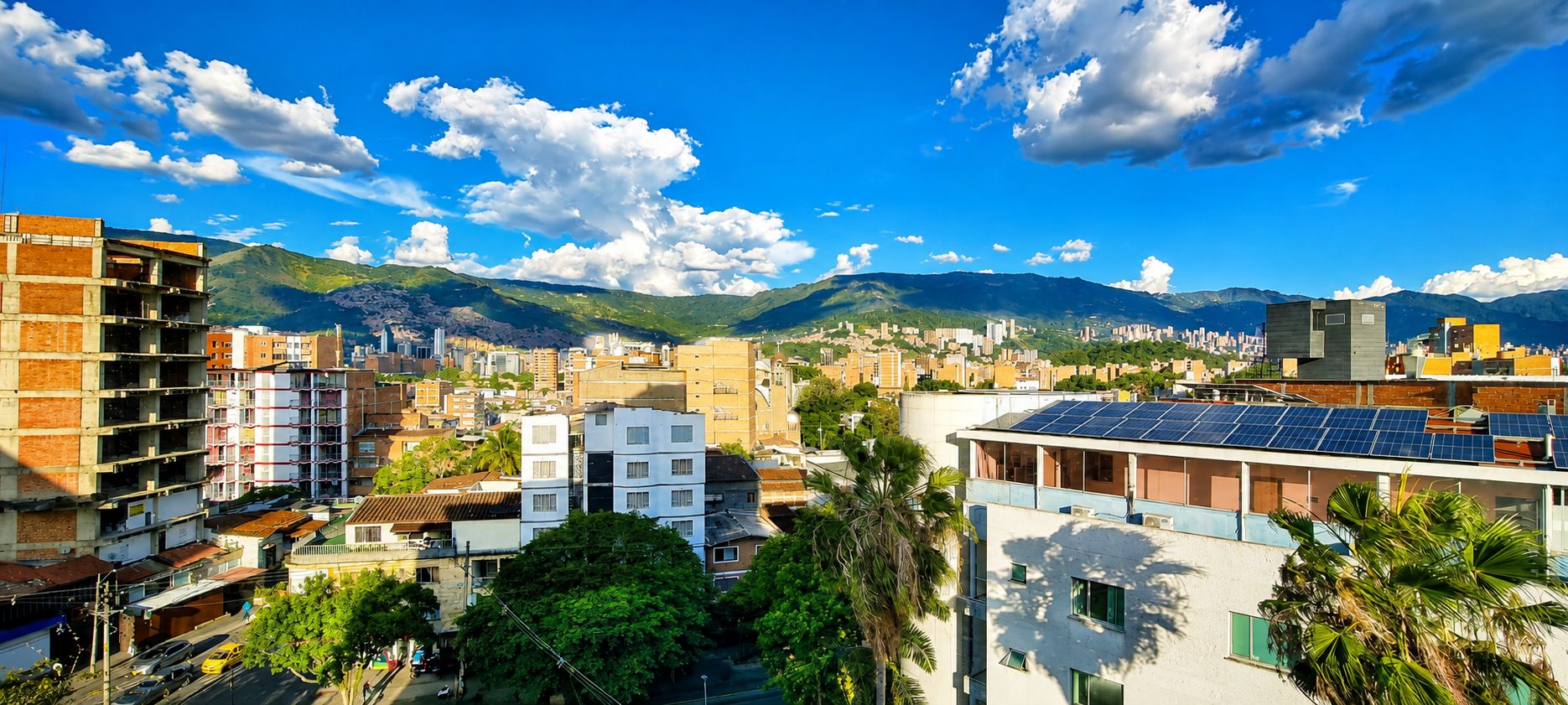A cityscape with buildings, a road, and mountains in the background.