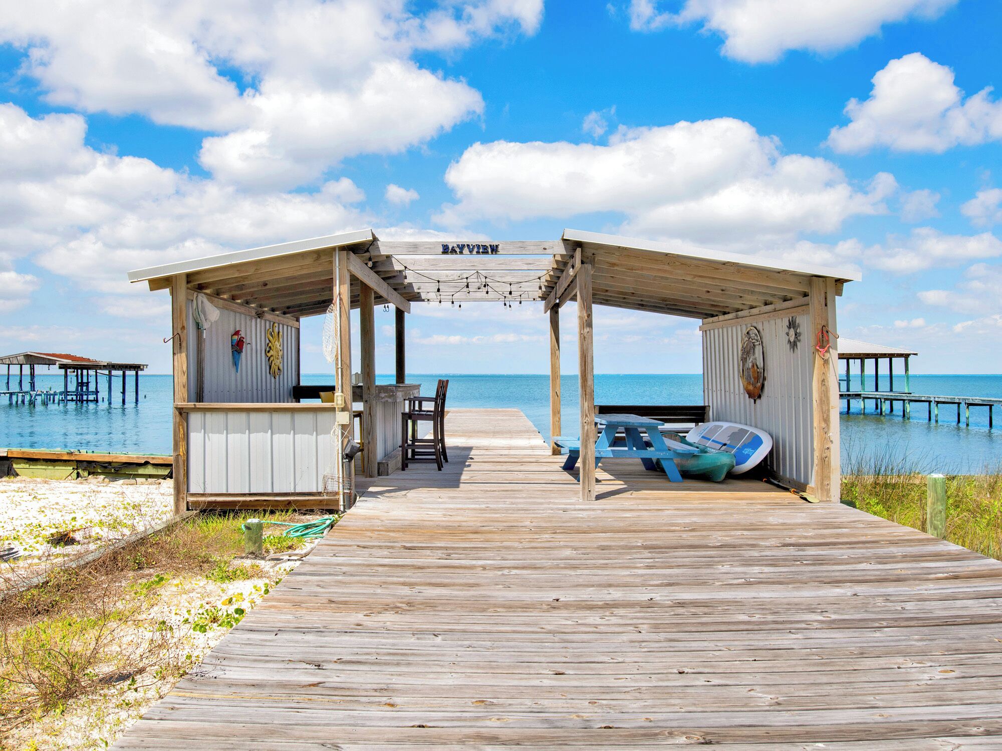 A wooden pier leading to a covered area with a view of the sea.