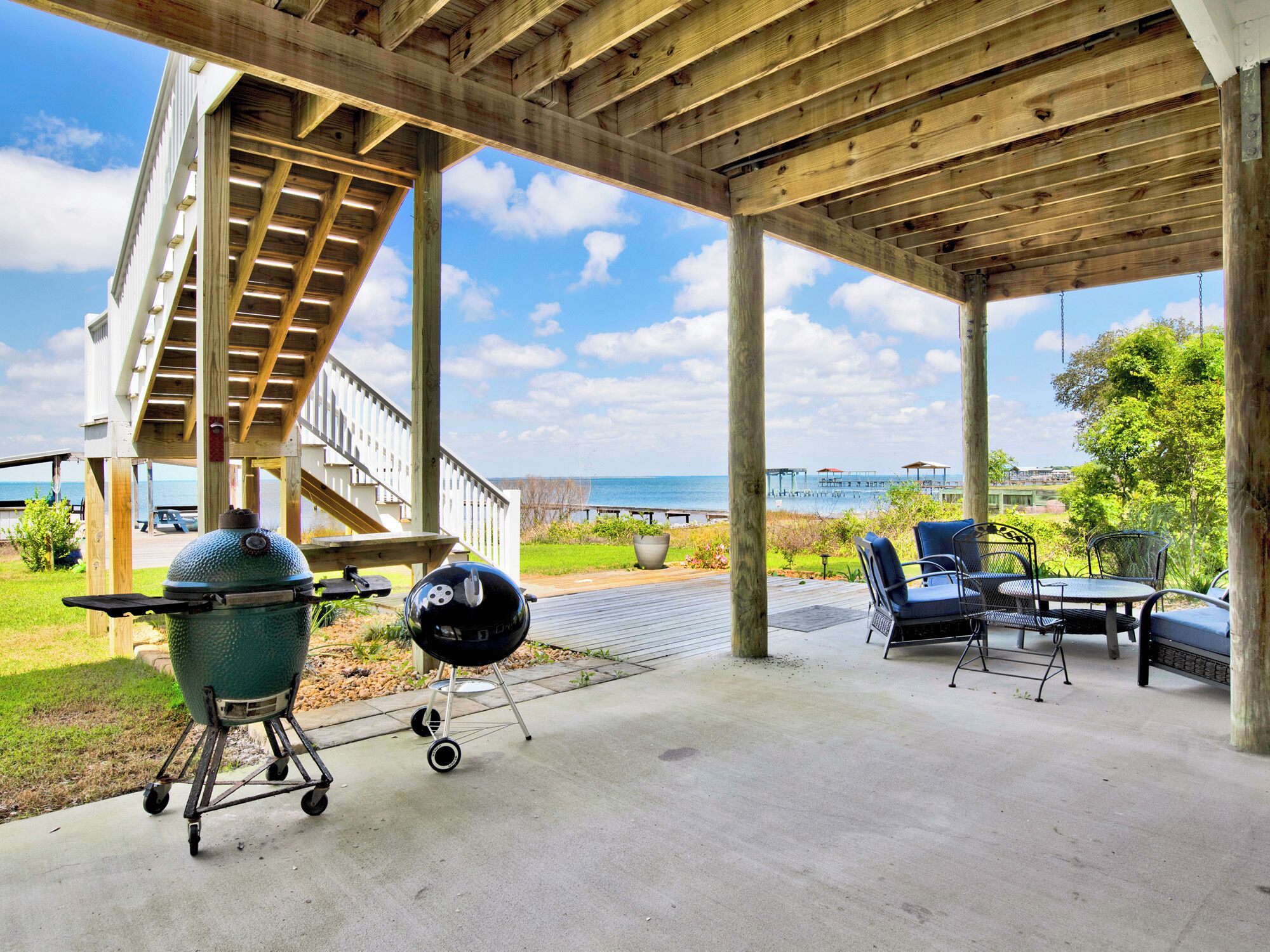 An outdoor patio with a wooden pergola, a grill, and outdoor furniture.