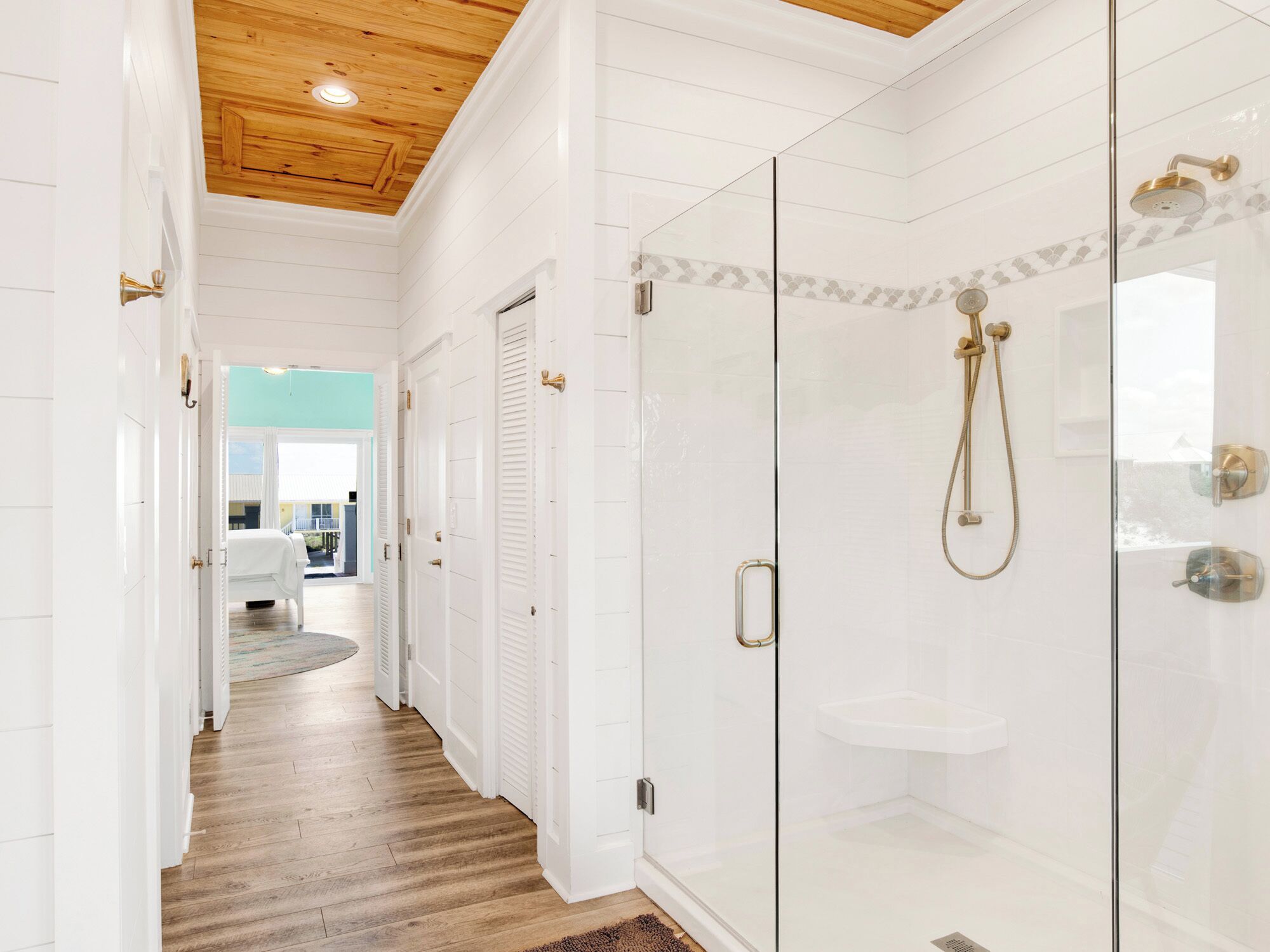 A modern bathroom with a glass-enclosed shower, white tiled walls, and a wooden ceiling.