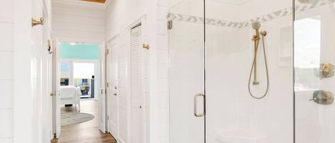 A modern bathroom with a glass-enclosed shower, white tiled walls, and a wooden ceiling.