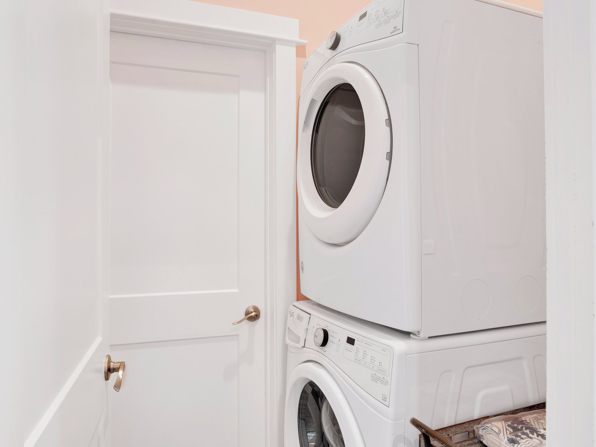 A laundry room with stacked washing machines and a closed door.