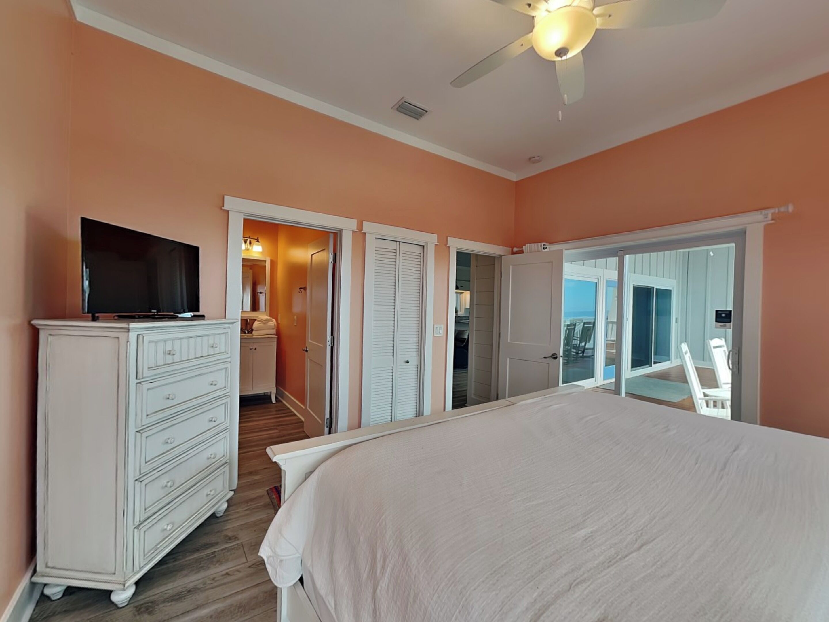 Une chambre à coucher comprenant un lit, une commode, un téléviseur et un ventilateur de plafond.