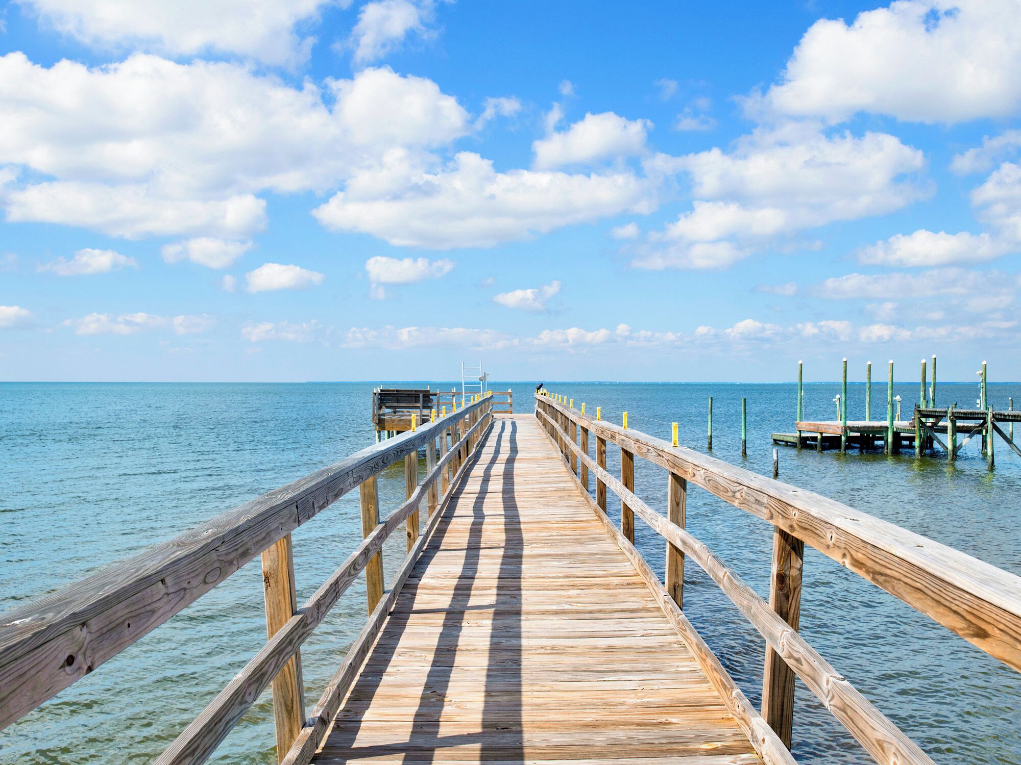 Un muelle de madera que se adentra en aguas tranquilas bajo un cielo despejado.