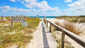 Une promenade en bois mène à une plage où un panneau indique : « CABANA BEACH ».