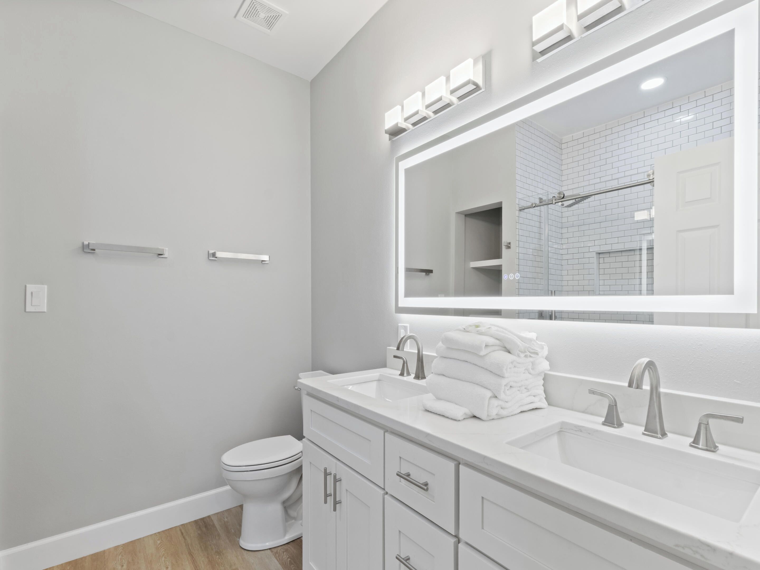 A modern bathroom with a white sink, vanity, and toilet.