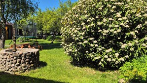Ein Garten mit einem Stebrunnen, einer hölzernen Bank und einem üppigen Blütenstrauch.