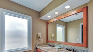 Une salle de bain avec deux lavabos, un grand miroir et une fenêtre.