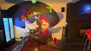 Un interior moderno con una mesa de madera, sillas rojas y arte abstracto en la pared.