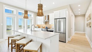A spacious kitchen with a large island, stainless steel appliances, and a view of the outdoors. - Just Beachy TC 6201 (Port Aransas)