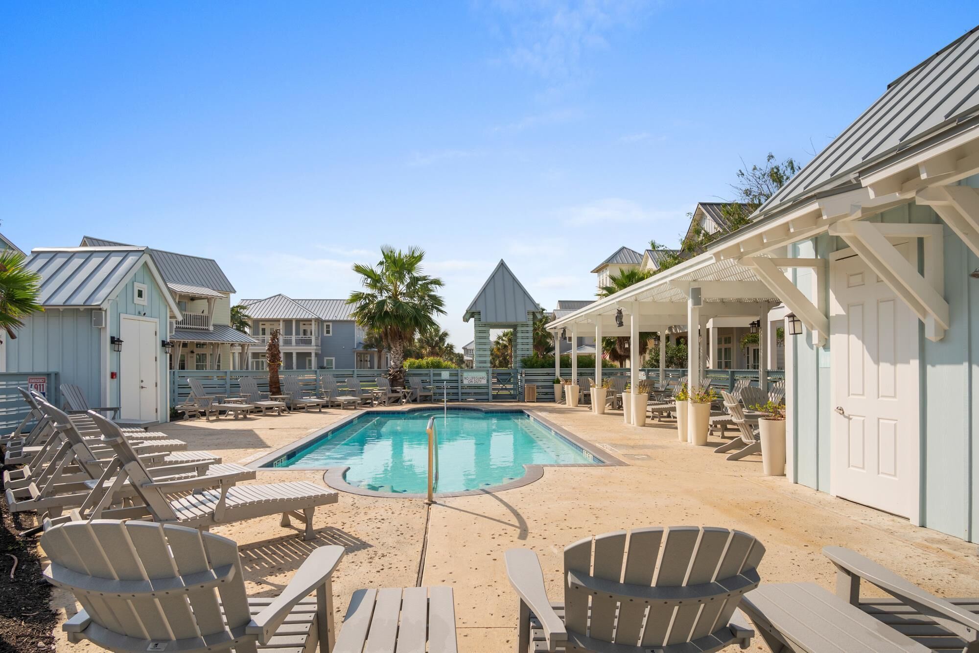 A pool area with lounge chairs and a covered seating area.