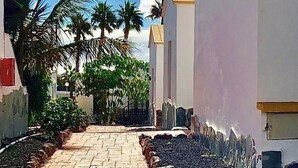 Un camino que lleva a una hilera de edificios blancos, bajo un cielo azul despejado y el sol.