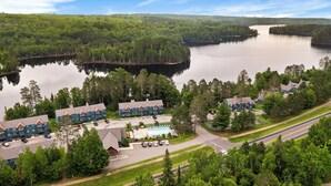 A lakeside resort with multiple buildings, a swimming pool, and a road leading to the property. - Hank's Lake & Links: The Legend (Biwabik)