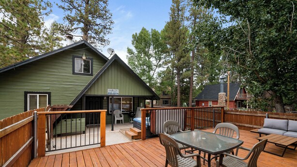 A wooden deck with a table and chairs, a sofa, and a covered area with a grill.