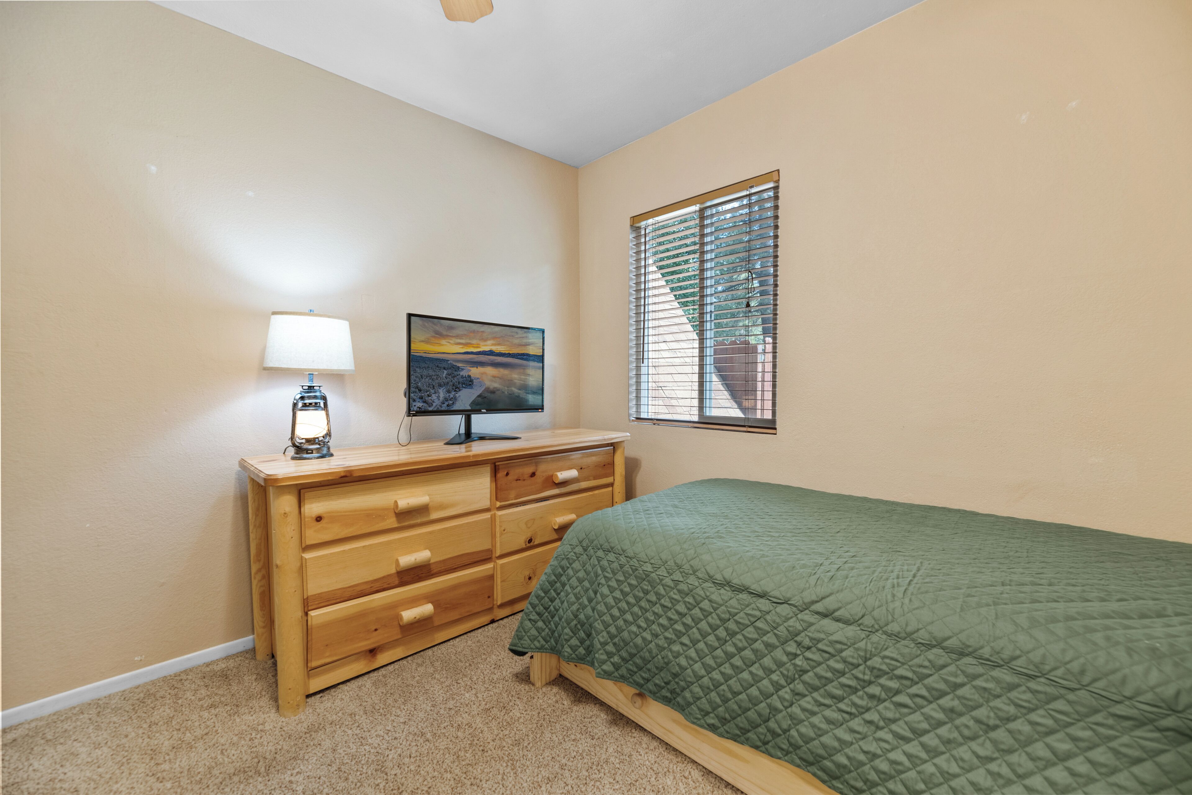 A bedroom with a bed, a dresser, a lamp, and a painting.