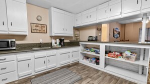 A kitchen with white cabinets, a microwave, a coffee maker, and a welcome sign.
