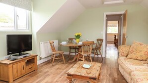 Una sala de estar acogedora con televisor, muebles de madera, una mesa de comedor con sillas y un sofá.